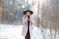 Young stylish blonde woman in an elegant black hat in a pink stylish coat in a black fashionable dress Royalty Free Stock Photo