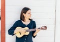 Young stylish brunette girl is playing ukulele