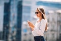 Young stylish business lady girl dials message on the phone. Hair develops dynamically, wearing a white shirt and stylish Royalty Free Stock Photo