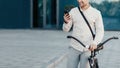 Young stylish businessman with smartphone in hand, with bike