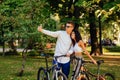 Young stylish couple in casual outfits are taking selfie on a smartphone in the city park, holding their bicycles. Cyclists are