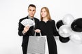 Young stylish couple, a man in a suit and a girl in a black dress, in her hands, balloons and bags, for shopping, a man holding c Royalty Free Stock Photo