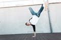 Young stylish dancer man in jeans in a fashionable shirt is standing on the hand outdoors. Handsome guy dancing break dance