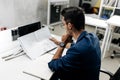 Young stylish dark-haired architect in glasses and in a blue jacket is working with documents on the desk in the office Royalty Free Stock Photo