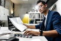 Young stylish dark-haired architect in glasses and in a blue jacket is working with documents on the desk in the office Royalty Free Stock Photo