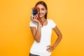 Young stylish girl photographer taking photo with retro camera. Portrait on yellow background Royalty Free Stock Photo