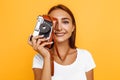 Young stylish girl photographer taking photo with retro camera. Portrait on yellow background Royalty Free Stock Photo