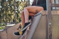 Girl`s legs with a tattoo. Young stylish girl sitting on a ramp in the skate park at the summertime. Royalty Free Stock Photo