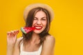 Young stylish girl in a straw hat with a lollipop on a yellow background. Summer concept with copy space. Girl bites off candy Royalty Free Stock Photo