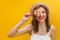 Young stylish girl in a straw hat with a multicolored lollipop on a yellow background. Summer concept with copy space. Girl covers Royalty Free Stock Photo