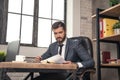 Young stylish handsome businessman reading documents at his desk in the office Royalty Free Stock Photo