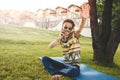 Young stylish handsome smiling man with sunglasses is sitting on grass, resting and talking on the phone. waves his hand welcoming Royalty Free Stock Photo