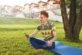 Young stylish handsome man is sitting on grass and talking on the phone resting in the park. Taking a Break Royalty Free Stock Photo