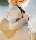 Young stylish hipster girl wearing modern trench coat walking in urban city with the fashionable shoulder bag, autumn Royalty Free Stock Photo