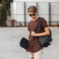 Young stylish hipster man in trendy sunglasses in a stylish T-shirt in trendy shorts with a sports backpack with a skateboard Royalty Free Stock Photo