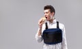 Young stylish male worker with chest rig bag is eating a tasty juicy burger on a white background Royalty Free Stock Photo