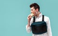 Young stylish male worker with chest rig bag is eating a tasty juicy burger on a white background Royalty Free Stock Photo