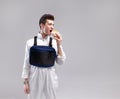 Young stylish male worker with chest rig bag is eating a tasty juicy burger on a white background Royalty Free Stock Photo