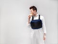 Young stylish male worker with chest rig bag is eating a tasty juicy burger on a white background Royalty Free Stock Photo