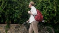 Young stylish man with bag walking with bicycle at park Royalty Free Stock Photo