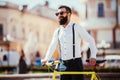 Young stylish man going to work by bike. hipster with a fixie bicycle on the street. bearded man looking away while riding on his Royalty Free Stock Photo