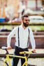 Young stylish man going to work by bike. hipster with a fixie bicycle on the street. bearded man looking away while riding on his Royalty Free Stock Photo