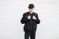 Young stylish man hipster in a black cap in sunglasses in stylish jeans in a black bomber jacket with a backpack Royalty Free Stock Photo