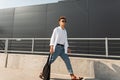 Young stylish man hipster in trendy clothes in sunglasses with a black cloth bag in vintage sandals walks is in a city Royalty Free Stock Photo