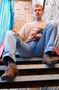 Young stylish man sit on stairs near brick wall.