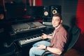 Young stylish man sitting on chair in front of monitor and soundboard