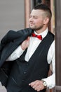 Young stylish man in a suit. Portrait of the groom. The groom is holding his jacket on his shoulder, side view Royalty Free Stock Photo