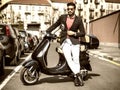 Trendy man by scooter in city