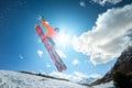 A young stylish man in sunglasses and a cap performs a trick in jumping with a kicker of snow against the blue sky and Royalty Free Stock Photo