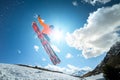 A young stylish man in sunglasses and a cap performs a trick in jumping with a kicker of snow against the blue sky and Royalty Free Stock Photo