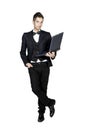Young stylish man in tuxedo holding laptop