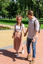 Stylish multicultural couple holding hands while walking in park