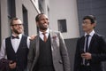 Young stylish multiethnic businessmen in formalwear walking outdoors