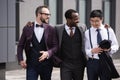 Young stylish multiethnic businessmen in formalwear walking outdoors