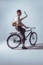 young stylish musician in sunglasses holding saxophone and riding bicycle