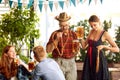 Young stylish people in bavarian clothes drinking beer and eating lager beer at pub. Friends meeting for celebration Royalty Free Stock Photo