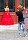 Young stylish photographer taking a picture of a beautiful girl in red dress for wedding portfolio