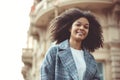 Young stylish positive african american woman crossing zebra and smiling at camera while walking in city Royalty Free Stock Photo