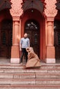 Young stylish pretty couple of hipsters in love are having fun in the city near castle in spring. young blond woman in red dress Royalty Free Stock Photo