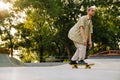 Young stylish short-haired boy riding skateboard in sunny skatepark Royalty Free Stock Photo