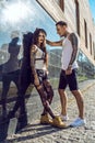 Young stylish tattooed couple at the black tiled wall on the street