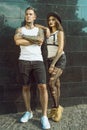 Young stylish tattooed couple standing at the tiled black wall on the street