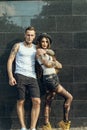 Young stylish tattooed couple standing at the tiled wall on the street