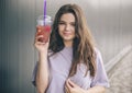 Young stylish trendy woman isolated over grey blue background. Cheerful positive girl posing on camera with plastic cup