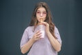 Young stylish trendy woman isolated over grey blue background. Emotional girl drinking milk cocktail and look straight Royalty Free Stock Photo