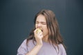 Young stylish trendy woman  over grey blue background. Picture of girl biting piece of white green apple Royalty Free Stock Photo